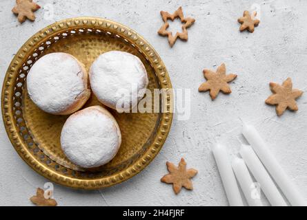 Overhead view of white candles and traditional Hanukkah jelly donuts on golden tray Stock Photo