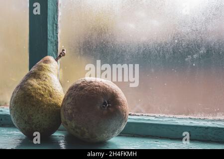 Two large pears after the fall harvest on an old, misted blue window. Rustic simple still life. Stock Photo