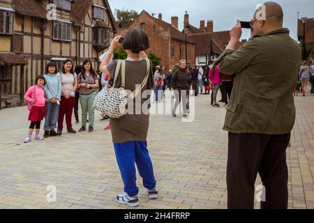 A family pose for photographs outside of William Shakespeare's birthplace in Stratford Upon Avon, England, United Kingdom. Stock Photo