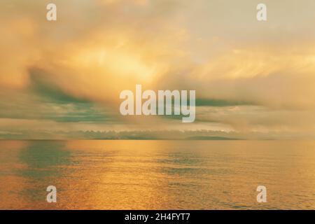 Summer landscape. Beautiful clouds over sea. Sunlight through clouds. Beach with trees on horizon. Travel background. Stock Photo