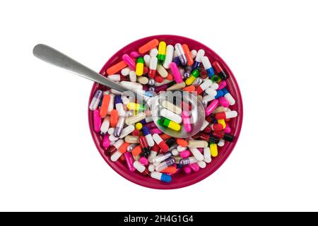 Bowl and spoon filled with colorful pills and capsules. Stock Photo