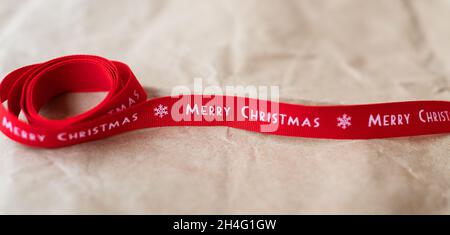 Banner. Red ribbon with the words Merry Christmas spread out on craft paper. Place for an inscription Stock Photo