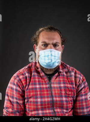 Portrait of angry man wearing facial mask as virus protection concept, shoot in studio Stock Photo