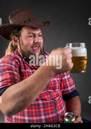 Portrait of funny young man drinking beer from mug in studio Stock Photo