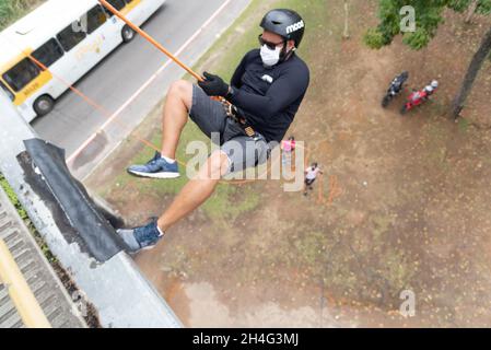Man wearing face mask and rappelling on the Lapa catwalk in Salvador, Bahia, Brazil. Stock Photo