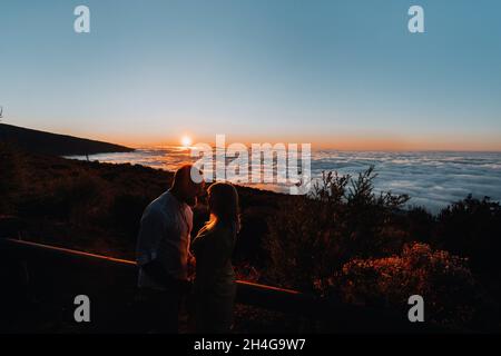 A loving man holds the girl s hand at sunset, on the background of the sea, portrait of handsome newlyweds. Photograph, concept Stock Photo