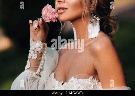 times in a woman's hand, she takes a rose, bride's fees, morning bride, white dress, put on earrings. Stock Photo