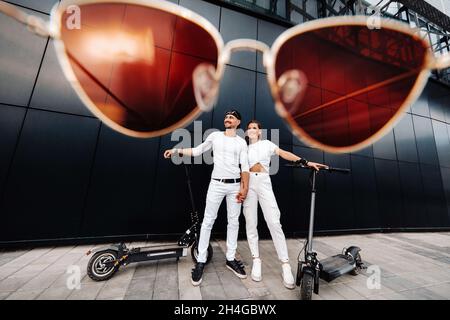 A girl and a guy are walking on electric scooters around the city, a couple in love on scooters Stock Photo