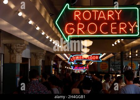 Crowds inside Public Market Center/Pike Place Market with neon signs of stores.Seattle.Washington.USA Stock Photo
