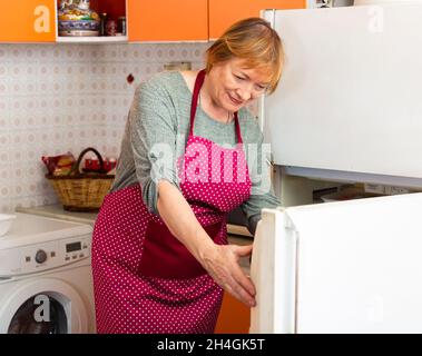 Elderly woman cooks preparing food in the kitchen Stock Photo