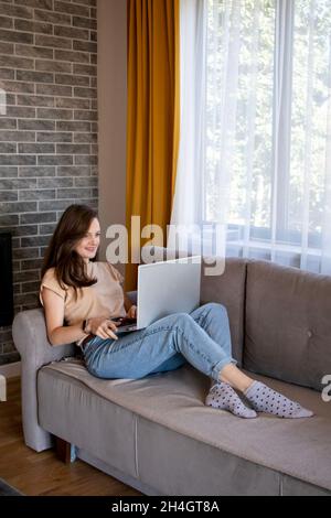 Comfortable studying at home. A young woman is learning remotely with a laptop.  Stock Photo