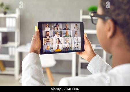 Woman holding tablet and having virtual business meeting with team of diverse people Stock Photo
