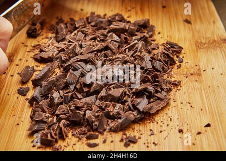 Chef cuts the chocolate with knife to make chocolate cake. Stock Photo