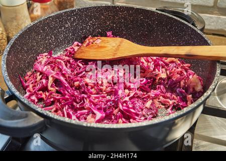 Red cabbage is fried in pan on gas stove. Stock Photo