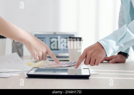 Two coworkers pointing at screen of digital tablet when discussing project of new application or website Stock Photo