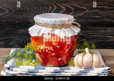 Homemade pickled red peppers in jars on wooden shelf Homemade canned and fermented foods concept Seasonal product. Stock Photo