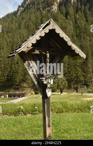 Vertical shot of a wooden wayside shrine with crucified Jesus figure Stock Photo