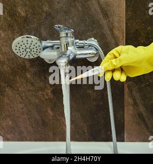 A woman checks the temperature of tap water with a thermometer Stock Photo