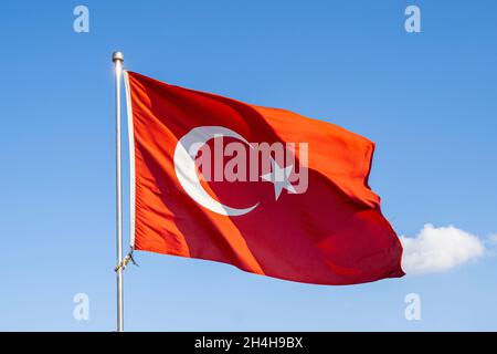 Turkish flag or flag of Turkey waving on flagpole against blue sky in Istanbul. Space for text. Stock Photo