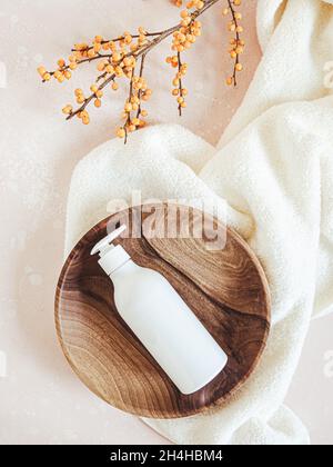 White plastic bottle with pump mock up, used for liquid soap, shampoo and lotion on wood tray on light background. Top view Stock Photo