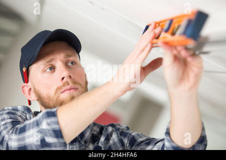 worker taking ceiling measures with spirit level Stock Photo
