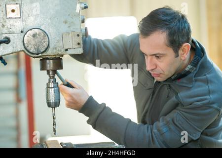 a workman using bench drill Stock Photo