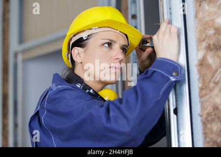 beautiful builder with measuring tape in new apartment Stock Photo