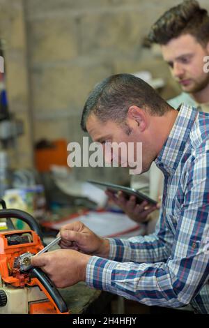 engineer and apprentice working on machine in factory Stock Photo