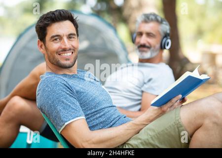 group of friends relaxing outside tents on camping holiday Stock Photo