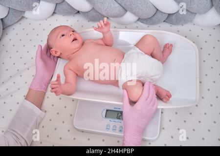 https://l450v.alamy.com/450v/2h4hpbp/the-doctor-weighs-a-newborn-baby-on-a-scale-uniformed-nurse-taking-measurements-of-the-child-weight-2h4hpbp.jpg