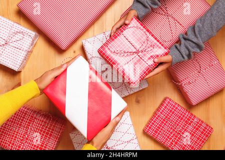 Close-up of womens and childrens hands giving each other gifts against the background of many presents. Top view Stock Photo