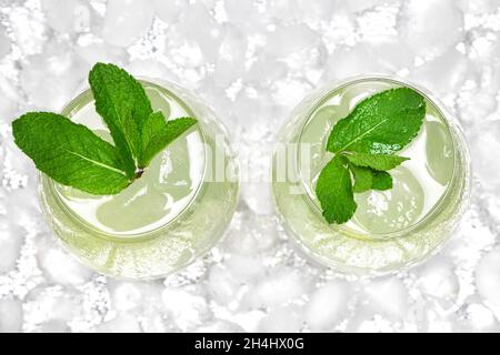 Refreshing drink with mint in large wine glasses surrounded by ice cubes. Close-up, top view. Cold mojito. Ice lemonade Stock Photo