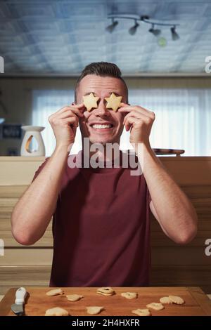 Funny portrait of young man during baking Christmas sweets at home kitchen. Stock Photo