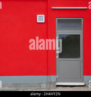 Detail of a red wall with a door, fluorescent tube and a fan Stock Photo