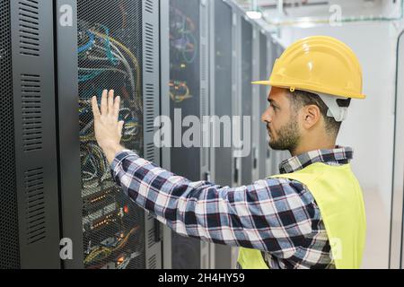 Young technician man working with tablet inside big data center room - Focus on man face Stock Photo