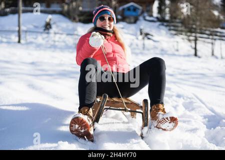Happy girl speeding with vintage sledding on snow high mountain - Focus on shoes Stock Photo