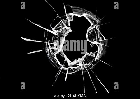 The glass hole shatters on the window from a bullet shot. Broken glass texture on a black background Stock Photo