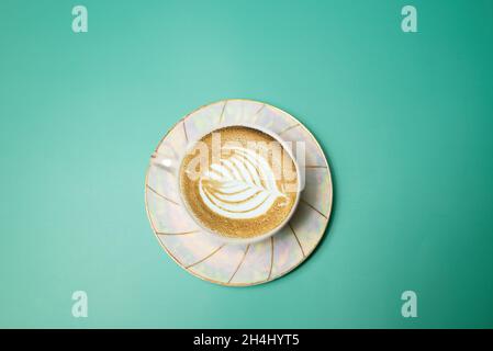 cup with coffee and cream in the form of a petal on a turquoise background Stock Photo