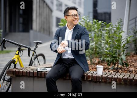Asian businessman drinking coffee on city street Stock Photo