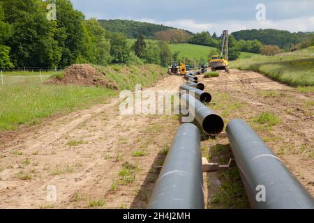 Various unplugged gas pipes lead in an idyllic landscape to the background with equippment to pipe laying Stock Photo