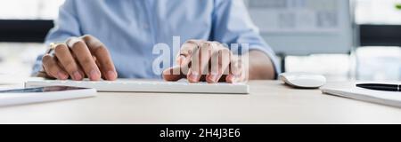 Cropped view of african american businessman using computer keyboard in office, banner Stock Photo