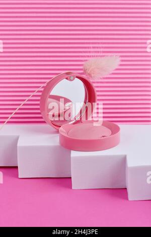 Round Blush in pink box with mirror on podium on a pink background. Cosmetic products. Stock Photo