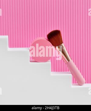 Round Blush in pink box with make-up brush on staircase podium. Cosmetic products. Stock Photo