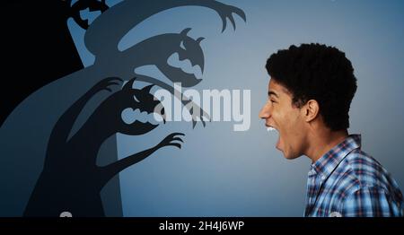 Side view of black teen guy screaming at scary monster silhouettes,fighting his inner fears on dark background, collage Stock Photo