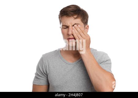 Sad tired unhappy millennial european attractive man rubs eye, suffers from pain and dryness Stock Photo