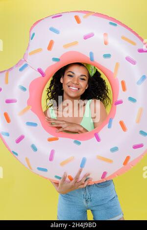 happy african american young woman holding inflatable ring isolated on yellow Stock Photo