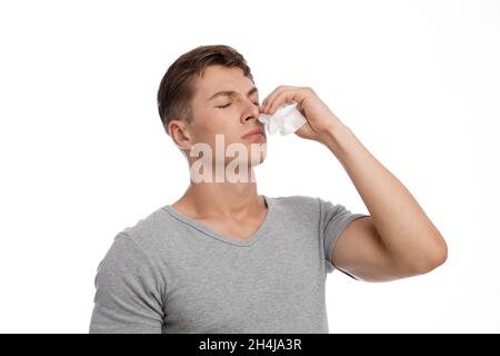 Disappointment sad young caucasian handsome guy presses napkin to nose and suffers bleeding or runny nose Stock Photo