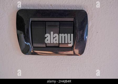 Black European switch close-up on the white wall. Electricity equipment. Interior design Stock Photo