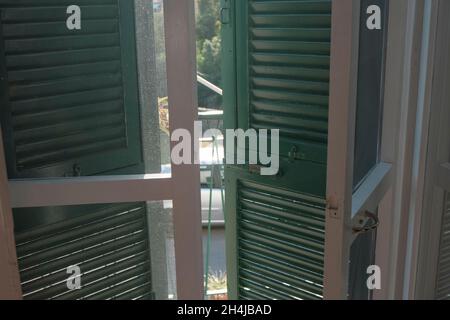 white windows with green window blinds of inside of the building on a sunny street. Home interior Stock Photo