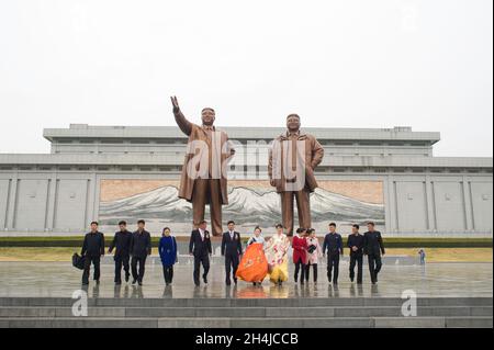 A wedding party in front of the statues of Kim Il-Sung and Kim Jong-il at Mansudae Hill Grand Monument in Pyongyang, North Korea. Stock Photo